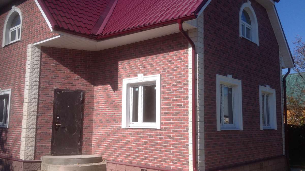 Деревянный дом, облицованный красной пестрой плиткой Деревянный дом, облицованный красной пестрой плиткой